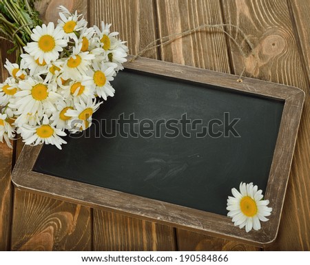 Writing board and daisies on a brown background