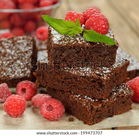 Chocolate brownies with raspberries on brown background
