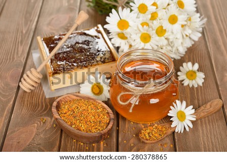 Honey, chamomile and pollen on a brown background