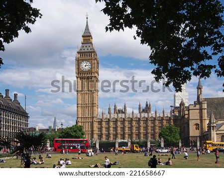 LONDON - AUGUST 5, 2013:  London\'s busy traffic moves around the Parliament Building as tourists rest in a shady park across the street, in London on August 5, 2013.