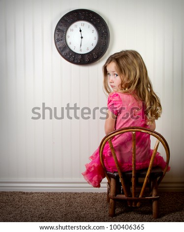little girl in time out or in trouble looking, with clock on the wall