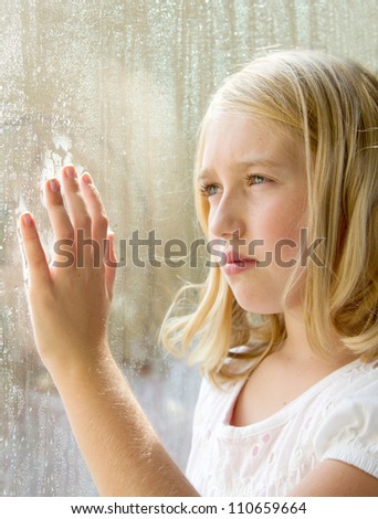 Teen or child looking out a window with rain
