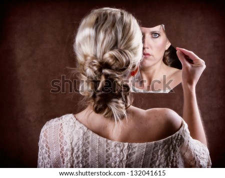 Woman looking into a broken mirror with back of head showing