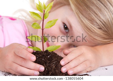 Young girl or child with a  plant while smiling, isolated on white.