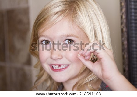 Child holding her missing front tooth