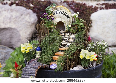 Fairy garden with a house made of a mushroom with a path and stairs in a flower pot
