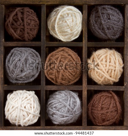 Assorted balls of natural colored yarn in a printers box