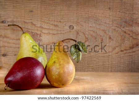 Three pears on a wooden plank with a wooden background