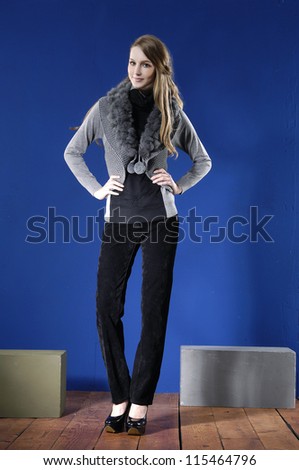 Full length young woman posing with cube with cube on wooden floor