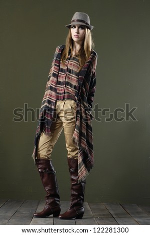 Beautiful fashion girl in hat standing posing on wooden floor
