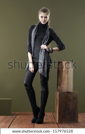 Full length portrait of young woman with wooden cube posing wooden floor