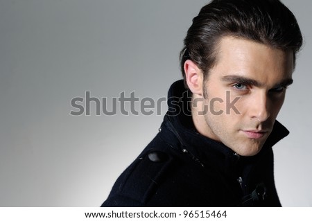 Handsome man casually leaning against in light background