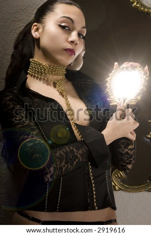 The girl with a gold beads on a neck and a small mirror in hands