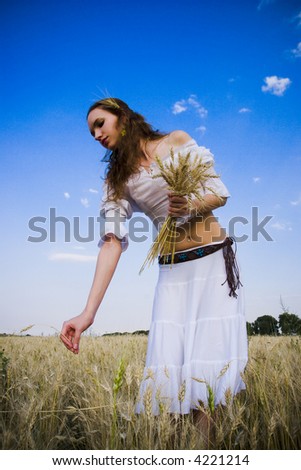 The woman in light clothes costing on a wheaten floor on a background of the dark blue sky