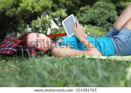 student in park with digital book and headphones
