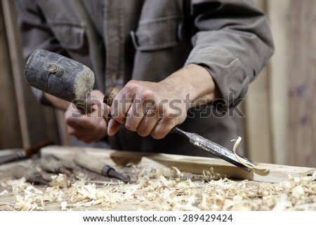 hands of carpenter with a hammer and chisel on the workbench in carpentry