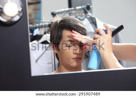 make up model at mirror in dressing room, sprays hairspray