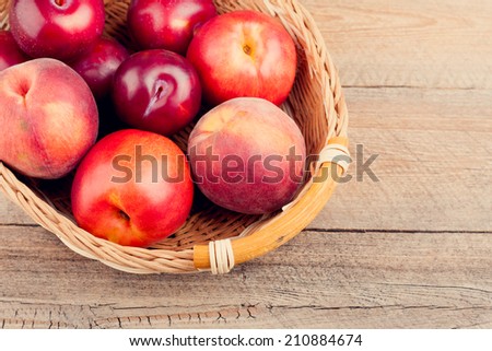 Plums, Peaches and Nectarines in a Woven Basket on Wooden Table