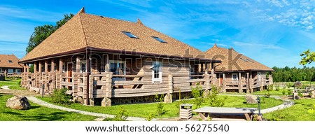 Old style wooden log cabins with blye sky and white clouds. Panoramic image from several shots