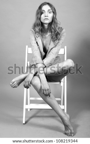 Young beautiful woman sitting on a chair in studio isolated