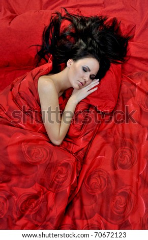 Pretty young woman sleeps on red linen