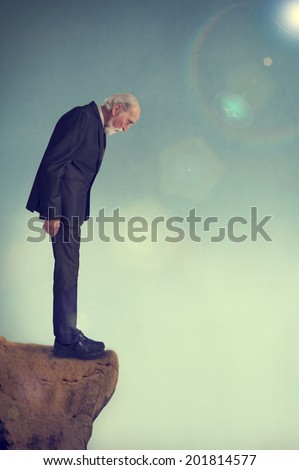 senior man standing alone on a cliff ledge