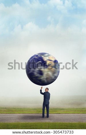businessman holding spinning planet earth aloft with one finger subtle vintage filter and selective focus with copy space