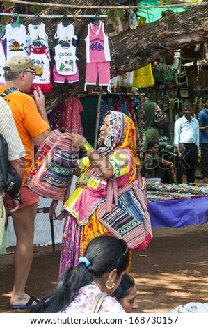 GOA, INDIA - FEBRUARY 20, 2013: Woman in authentic clothing offering people her goods on the Mandrem market on February 20, 2013 in Goa, India
