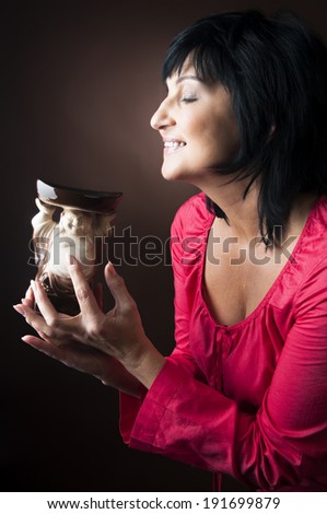 Mature woman smelling aromatherapy oil burner