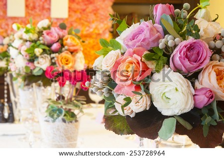Table with bouquets of roses and cyclamen plants setting for wedding