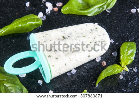 Homemade ice cream with basil leaves and salt on black stone background, top view