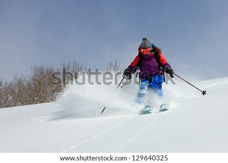 Smiling woman skiing through fresh powder snow in the Utah mountains, USA.