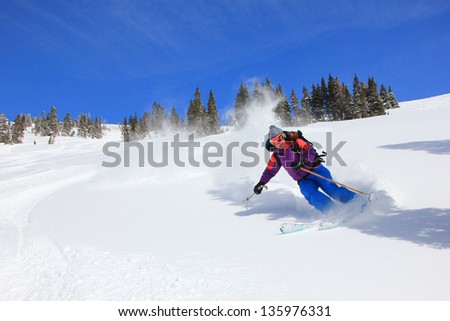 Amazing female skier blasting through powder snow in the Utah mountains, USA.