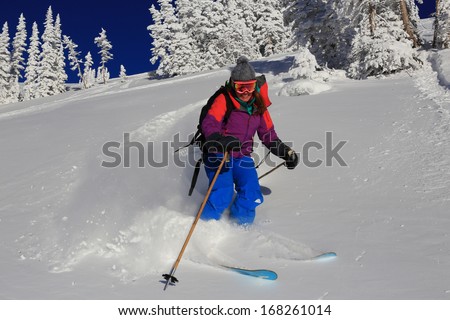 Smiling woman blasting through fresh powder snow in the Utah mountains, USA.