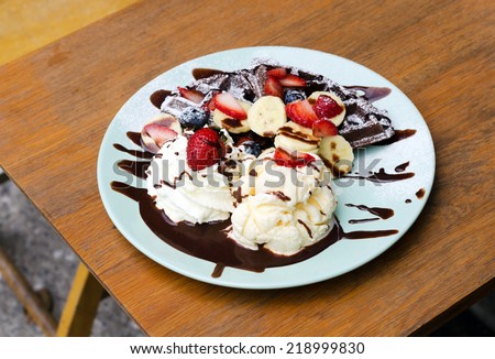 Ice cream, banana, strawberry, raspberry, chocolate waffles with chocolate sauce