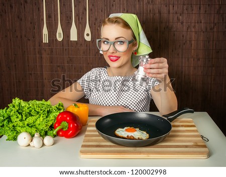 Happy funny woman cook holding salt over pan with fried egg - close up