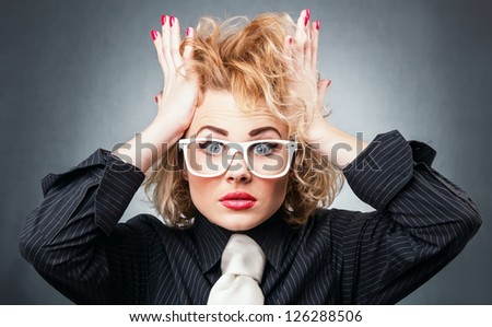 Shocked young business woman in a panic, isolated on gray