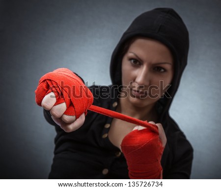Hard sport woman ready for fight. Fighter girl with hoodie over dark gray background