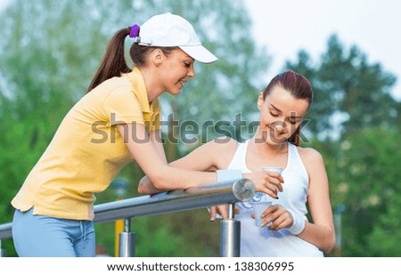 Friendship of two girl friends in sports clothing holding bottle water, together doing healthy lifestyle. Outdoors - outside
