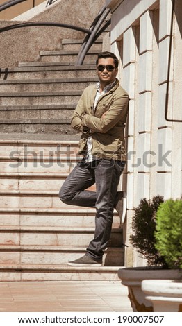 Young guy standing or posing, outdoor shot. Gorgeous macho man with crossed arms
