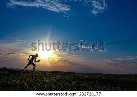 Silhouette man running on meadow, sunrise -sundown sky at background. Runner - sprinter on field