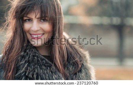 Attractive brunette with natural look, head shot of a young sexy woman on blurred background, soft sunny colors