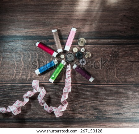Tools for sewing and handmade tailor or dressmaker. Thread, buttons,  and pins on wooden table. Diversity colors threads, above view