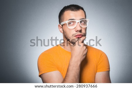 Thoughtful trendy guy thinking, isolated on gray background, studio shot