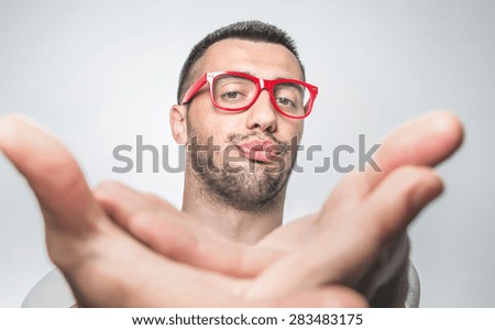Funny selfie. Young man holding camera and making selfie with facial expression. Purched lips. Nerd, close up isolated on gray background