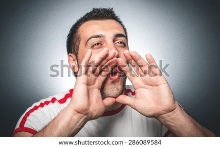 Closeup portrait mad funny man hands to open mouth yelling over dark gray background, studio shot