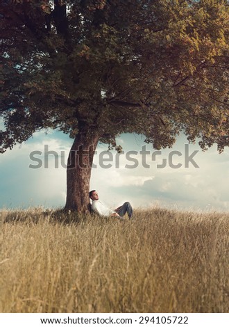 Carefree. Human relaxing under tree. Man repose on grass in nature. Outdoors - outside. Leisure concept. No worries. Art photo