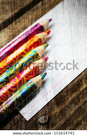 Colored wooden pencils on a sheet of white paper. Grunge style.