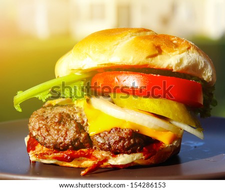 Delicious cheeseburger stacked high with a juicy beef patty, cheese, fresh lettuce, onion and tomato on a fresh bun with sesame seed