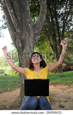 Woman on laptop with arms raised